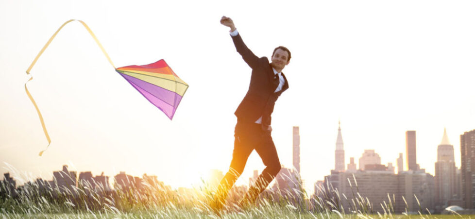 Photo of a businessman flying a kite with a city skyline in the background